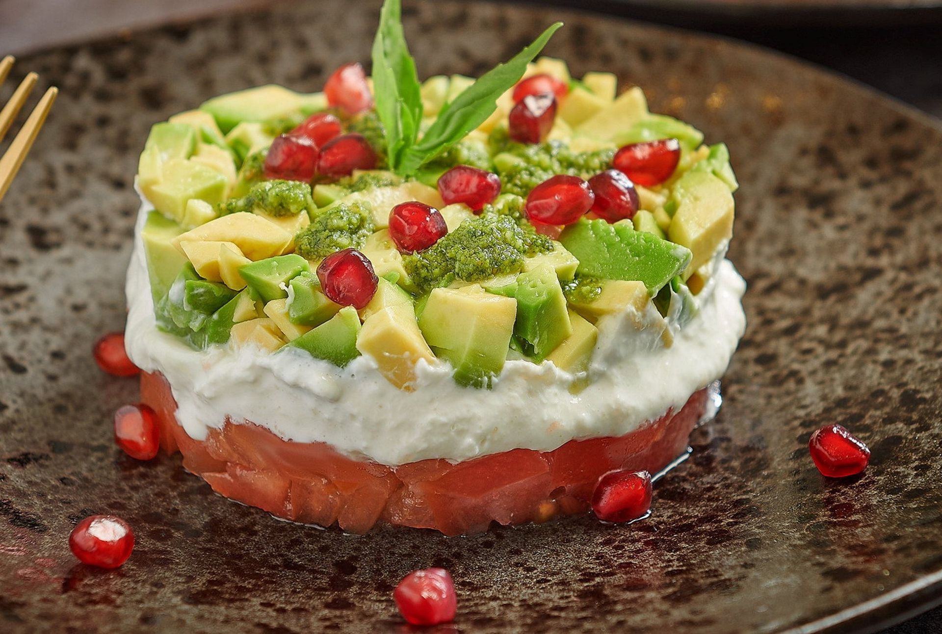 Lagvis forrett med tomat, kremet ost og avokado, toppet med granateplekjerner og pesto