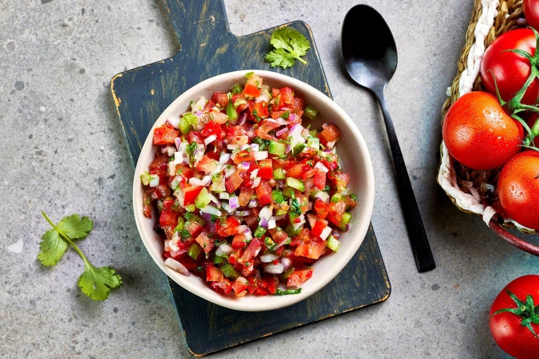 Skål med pico de gallo laget av finhakkede tomater, rødløk, grønn chili og koriander.