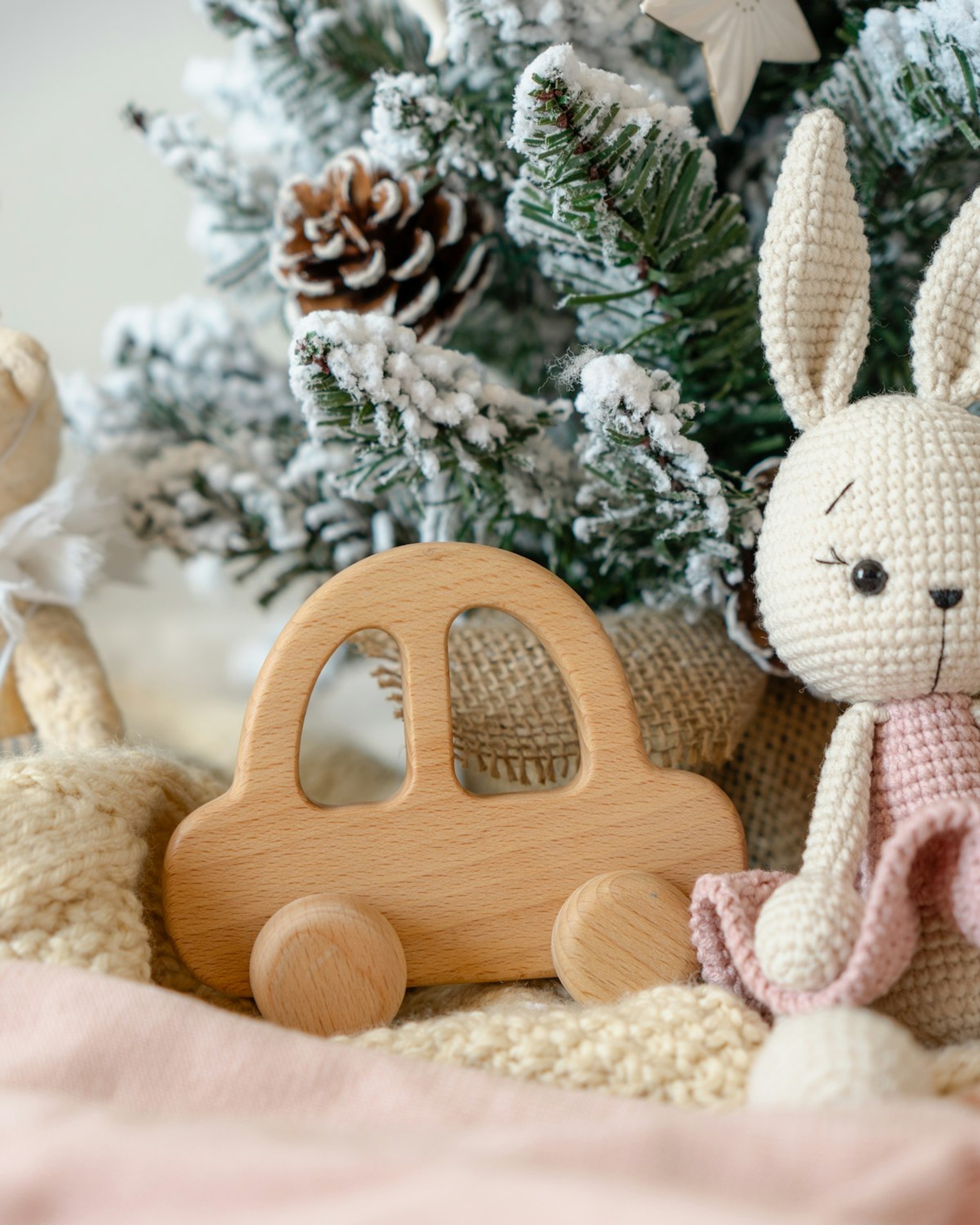 Crocheted bunny lovey beside a wooden toy car