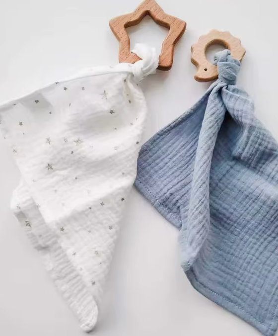 Wooden teething rings beside knitted blankets