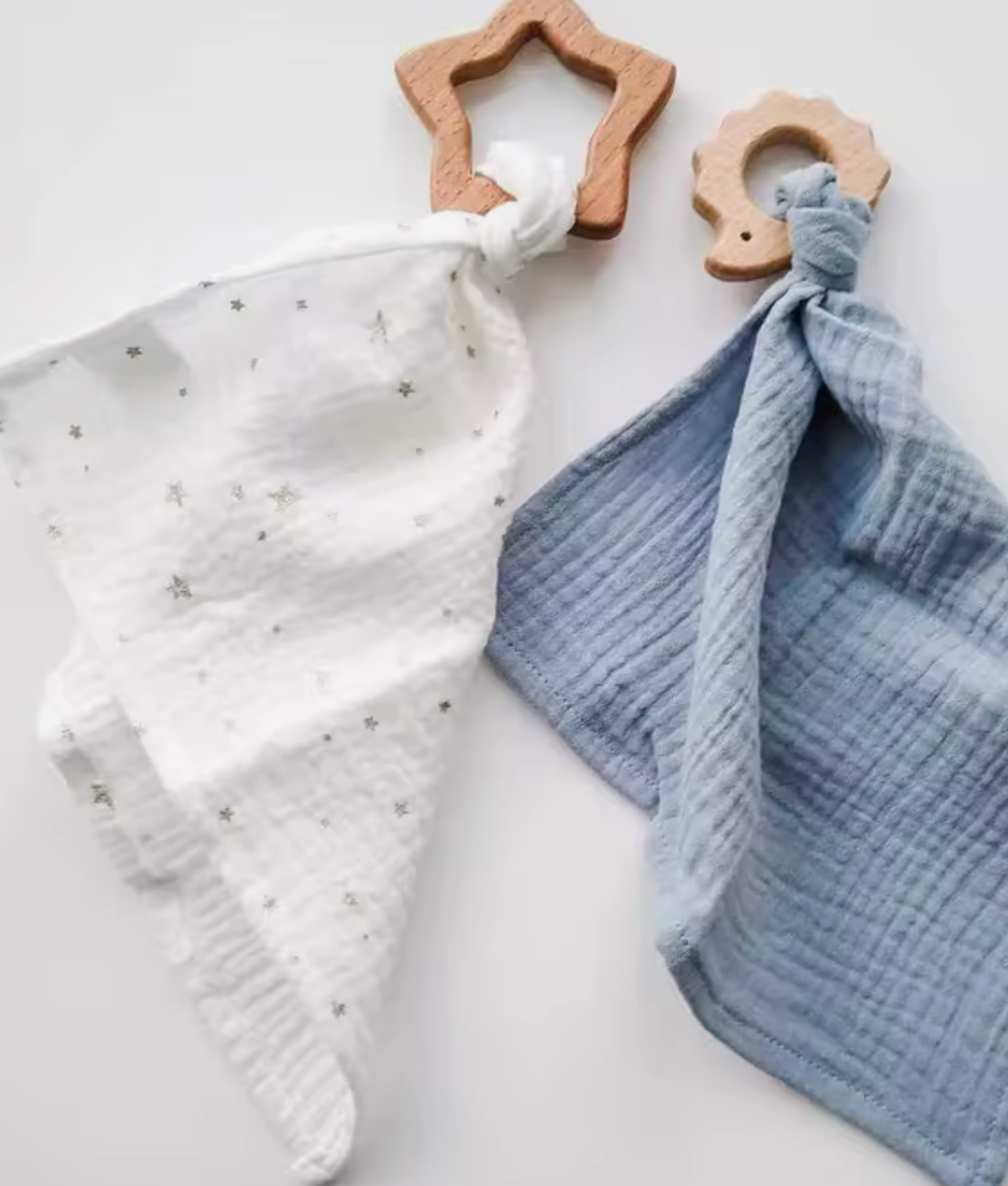 Wooden teething rings beside knitted blankets