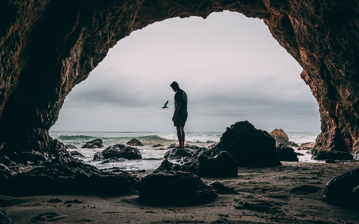 A man standing on a rock outside the cave