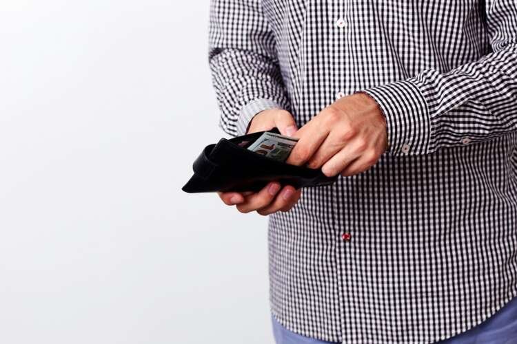 A hand pulling out $100 banknotes from a wallet, symbolizing financial literacy challenges - Global Banking & Finance Review