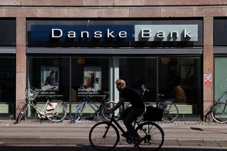 Bicycle rider passes a Danske Bank branch, highlighting banking's impact on financial scandals - Global Banking & Finance Review