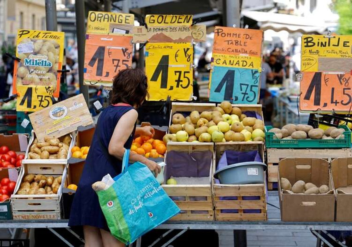 Woman shopping with price tags visible at a market in Nice, reflecting French inflation trends - Global Banking & Finance Review