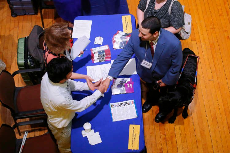 Job seeker interacting with potential employers at a job fair amidst high unemployment claims - Global Banking & Finance Review