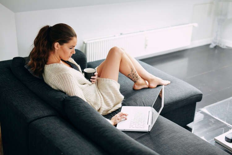 Young woman checking her emails on a sofa, reflecting on modern business communication - Global Banking & Finance Review