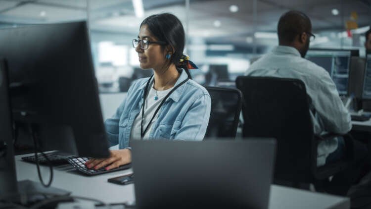 Diverse Office: Portrait of Talented Indian Girl IT Programmer Working on Desktop Computer in Friendly Multi-Ethnic Environment. Female Software Engineer Wearing Glasses Develop Inspirational App