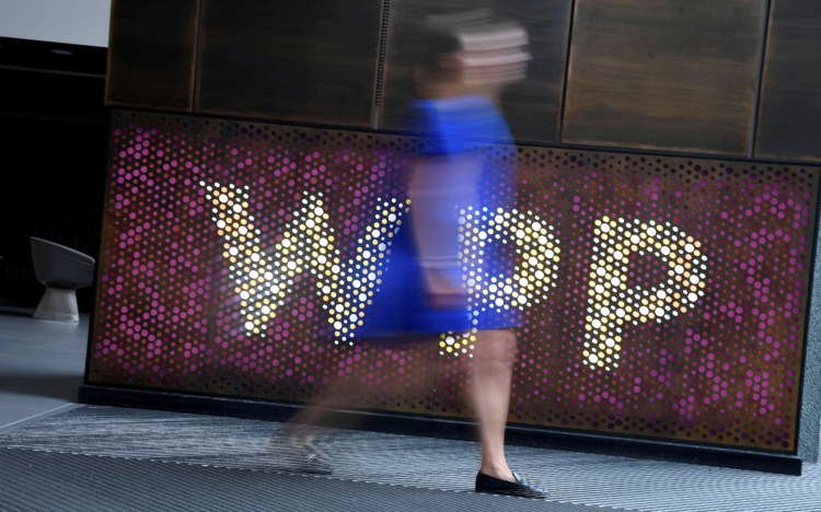 FILE PHOTO: A woman walks past signage for WPP at their offices in London