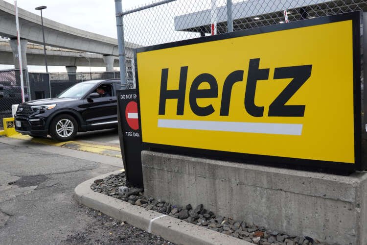 Car leaving Hertz rental lot with signage, highlighting wrongful theft report claims - Global Banking & Finance Review