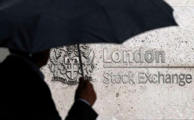 A man walks past the London Stock Exchange under an umbrella amid falling UK shares - Global Banking & Finance Review