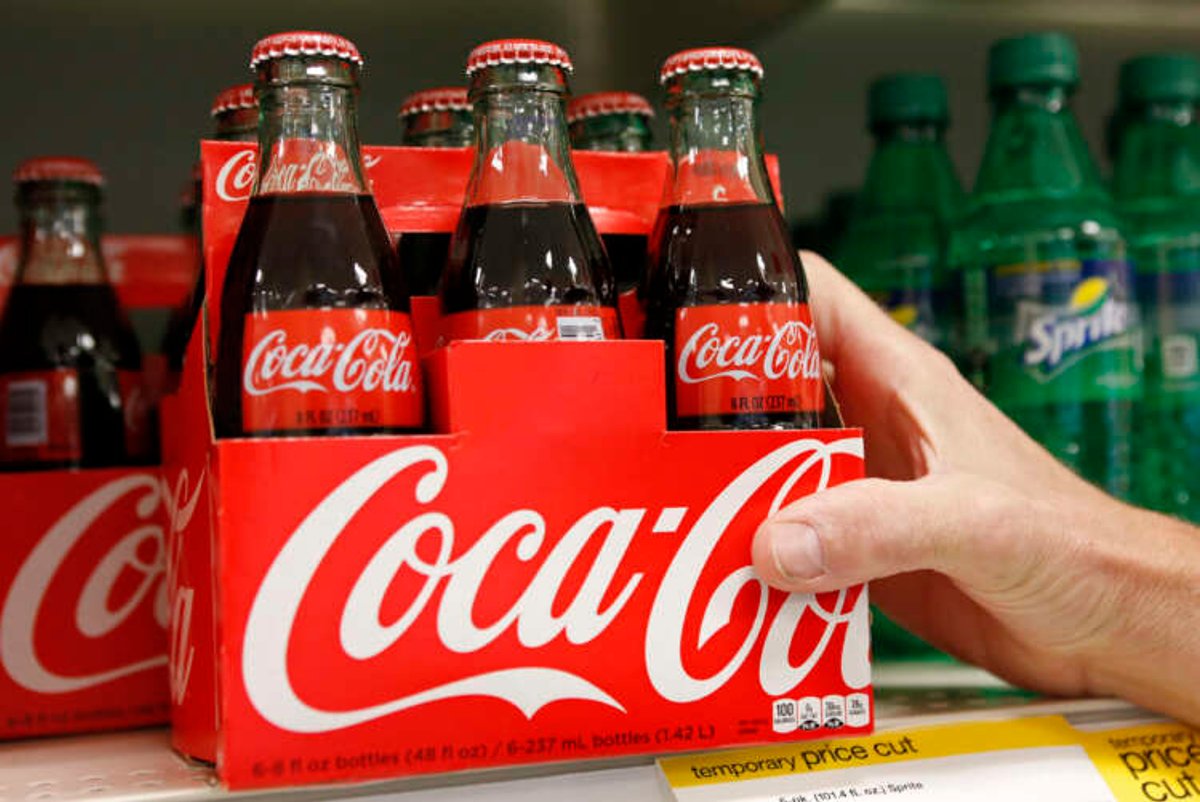 Coca-Cola employee arranging bottles in store, reflecting pricing strategies amid inflation - Global Banking & Finance Review