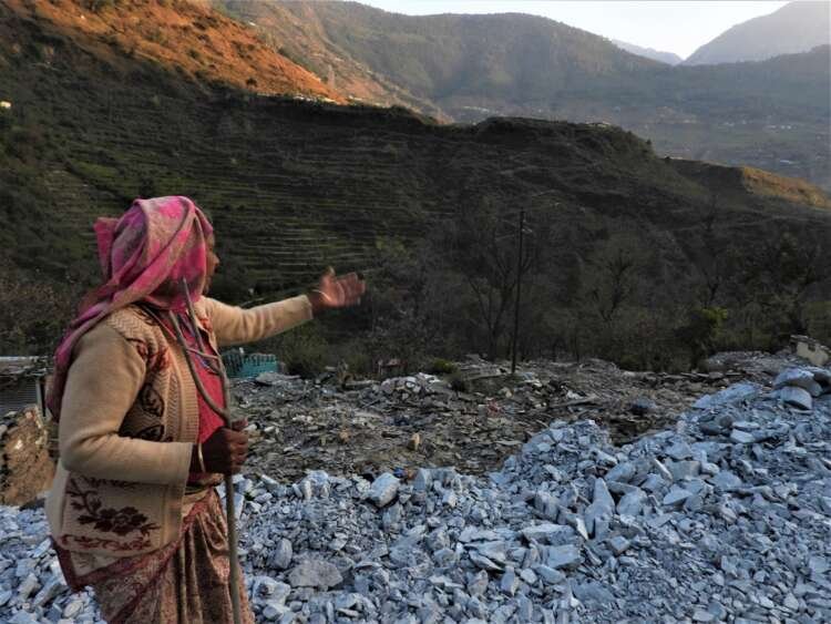 Narmada Devi points out where her house used to stand in Haat village before it was demolished as part of new hydropower project, in Chamoli, India, March 12, 2022. Thomson Reuters Foundation/Athar Parvaiz