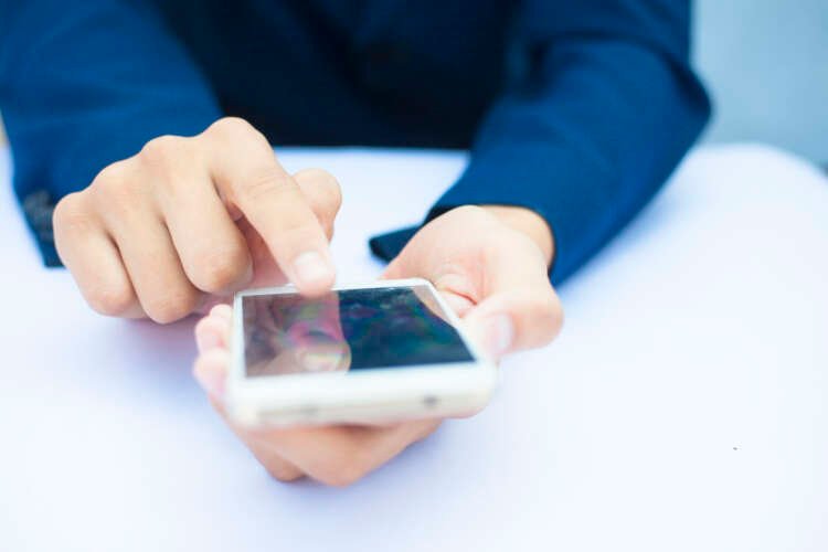 Businessman using smartphone for work, illustrating BYOD impact on cybersecurity - Global Banking & Finance Review