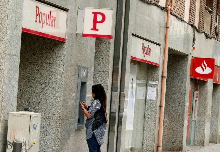 Woman using Banco Popular ATM near Santander office amid EU court ruling - Global Banking & Finance Review