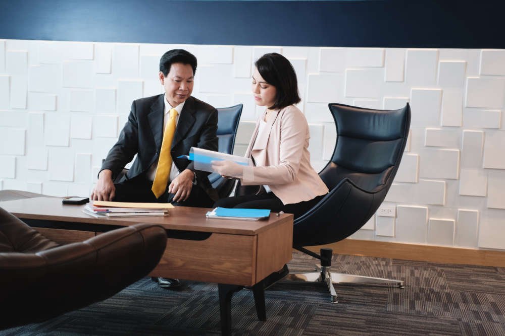 Investment Plan Agent Showing Documents To Asian Customer In Bank