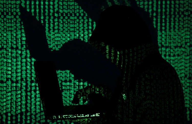 Man holds laptop computer as cyber code is projected on him in this illustration picture