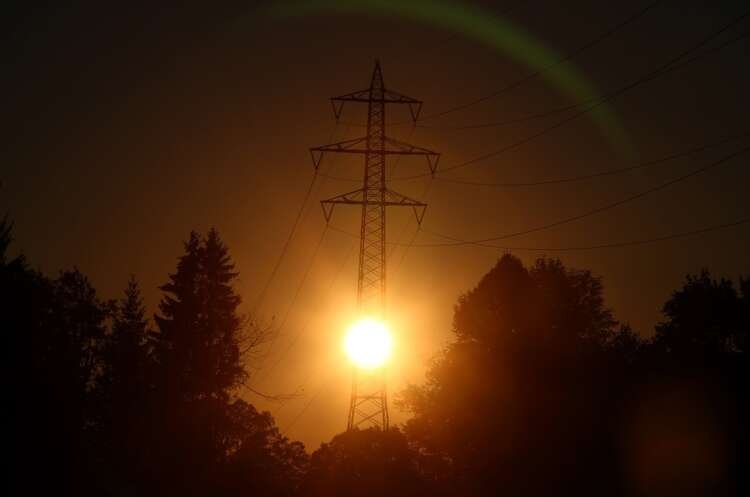 Morning sun illuminating high-voltage power lines crucial for Germany's gas price brake - Global Banking & Finance Review