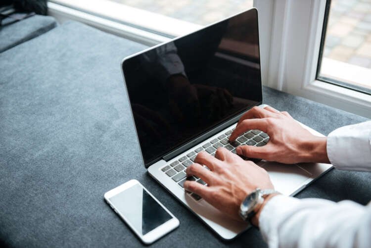 Cropped picture of handsome african businessman typing by laptop computer.