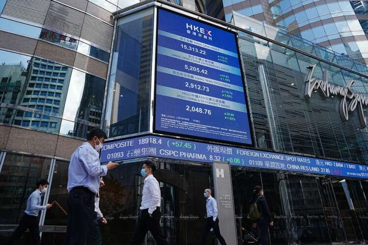 People walking past a stock market screen in Hong Kong during stock market rally - Global Banking & Finance Review