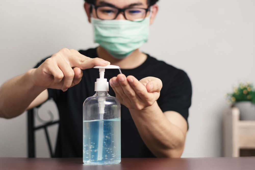 Asian man wearing glasses using antibacterial gel to prevent germs - Global Banking & Finance Review