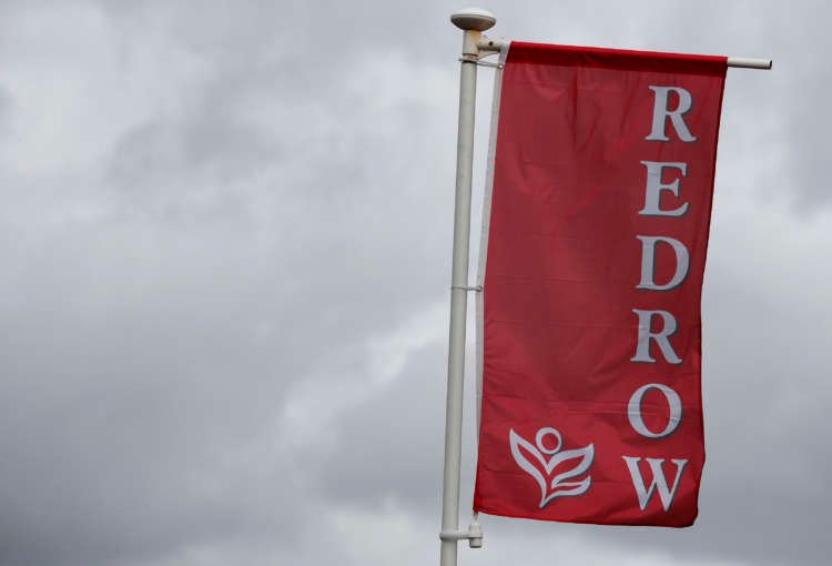 Redrow logo on a flag at a housing development, highlighting house buying tax debate - Global Banking & Finance Review