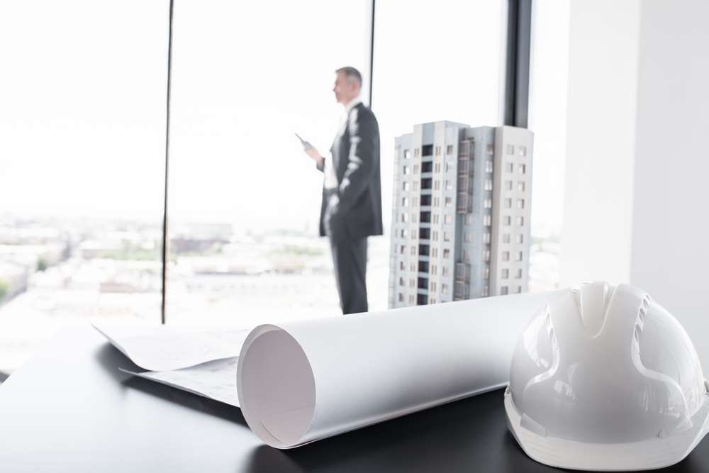 A person reviewing a construction business plan with architectural drawings - Global Banking & Finance Review