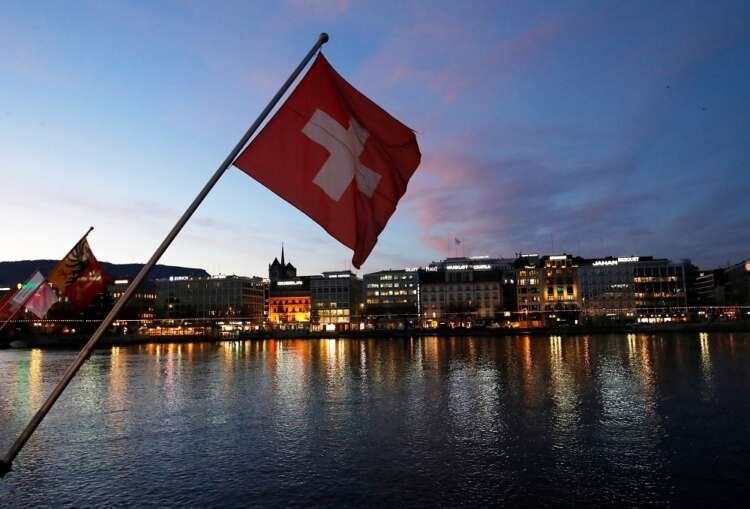Swiss flag during sunrise over Geneva's financial district - Global Banking & Finance Review