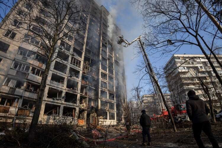 Firefighters work to put out a fire in a residential apartment building after it was hit by shelling in Kyiv
