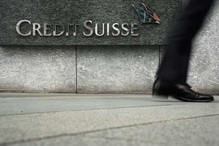 Pedestrian walks past Credit Suisse logo in Hong Kong, highlighting banking news - Global Banking & Finance Review