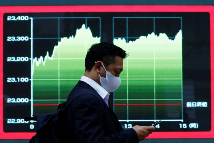 A man in a mask walks past a stock market display in Tokyo, reflecting cautious Asian shares amid rising bond yields - Global Banking & Finance Review