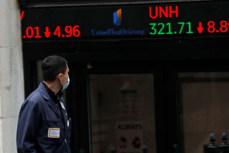 FILE PHOTO: A trader walks past a digital stock price display outside the New York Stock Exchange in New York