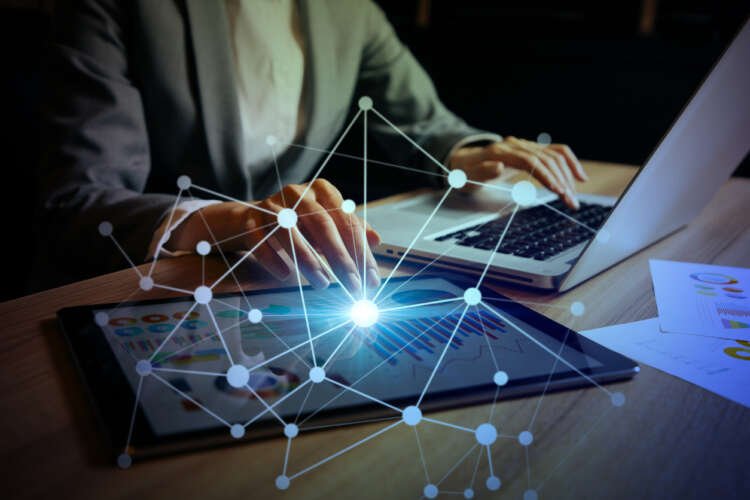 Businesswoman analyzing data on digital devices, highlighting system integration in mergers - Global Banking & Finance Review