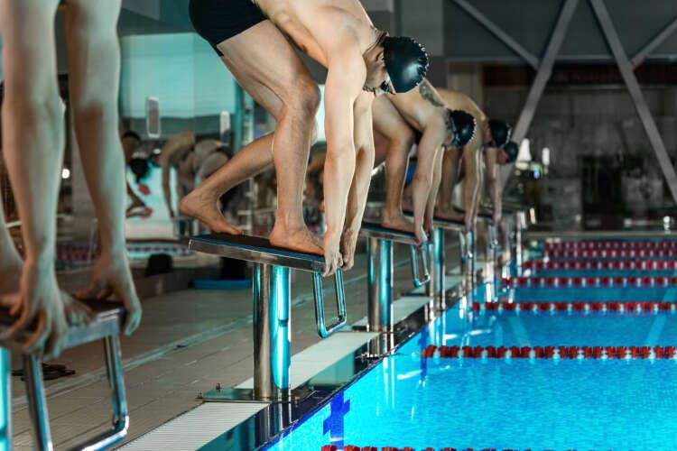 Men on starting blocks preparing for swimming competition at the Olympics - Global Banking & Finance Review