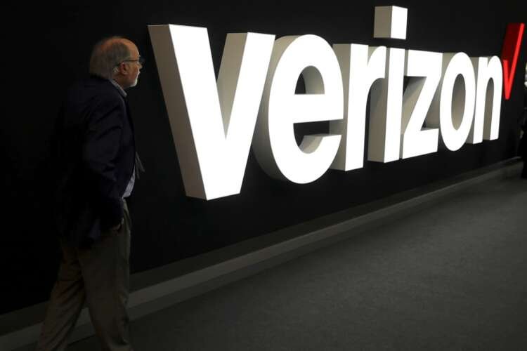 A man stands next to the logo of Verizon at the Mobile World Congress in Barcelona