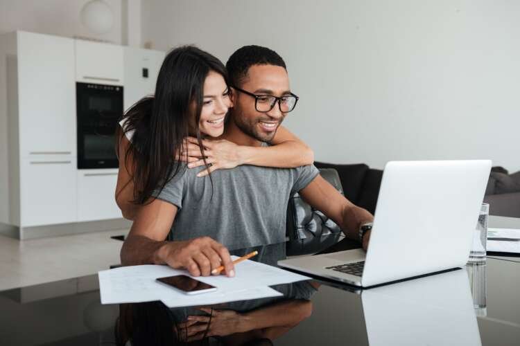 Happy couple analyzing finances on a laptop, reflecting property finance discussions - Global Banking & Finance Review