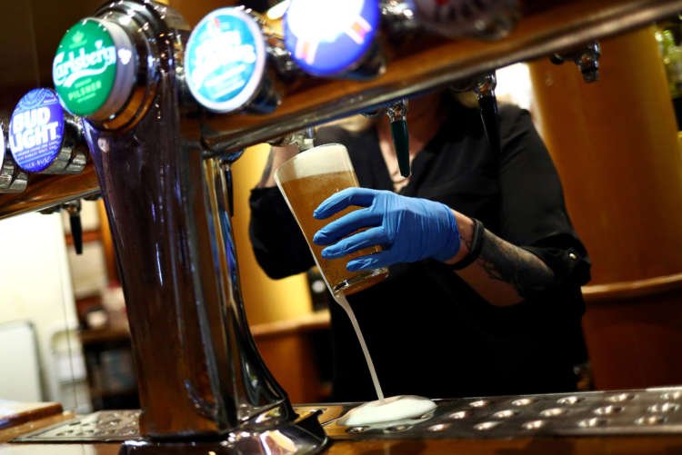 A bartender serving drinks at a pub, reflecting COVID-19's impact on spending - Global Banking & Finance Review