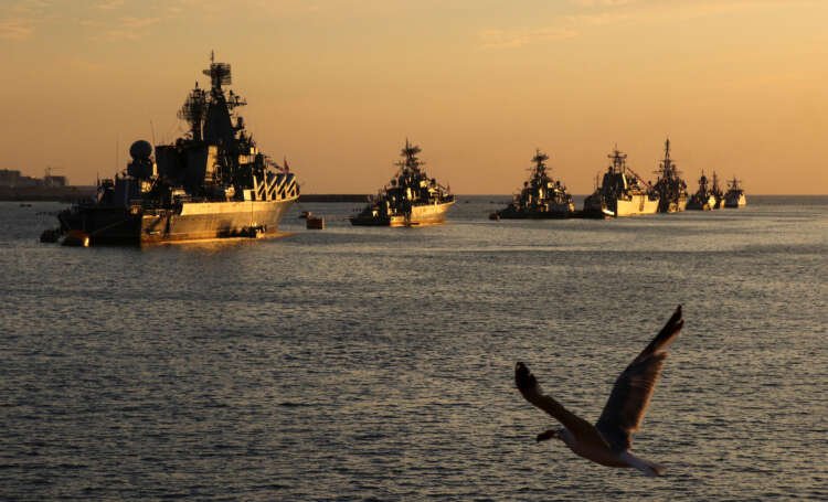 A seagull flies over Russian warships during sunset in the Black Sea, highlighting high-risk marine insurance areas - Global Banking & Finance Review