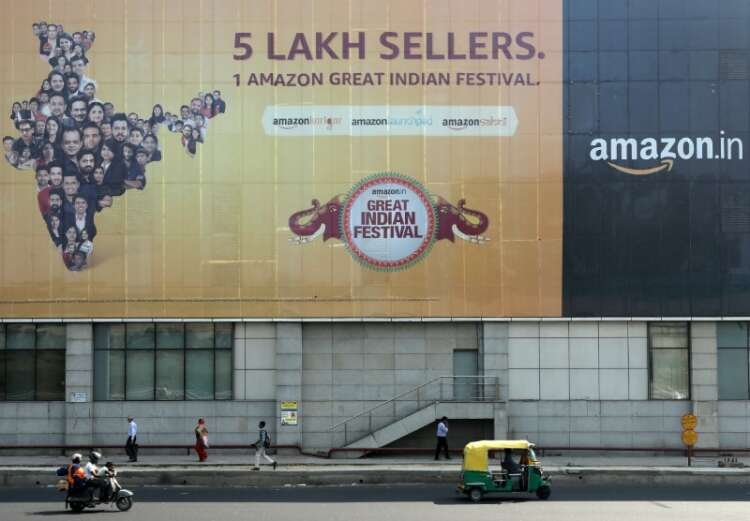 People walking past an Amazon India advertising hoarding in New Delhi - Global Banking & Finance Review