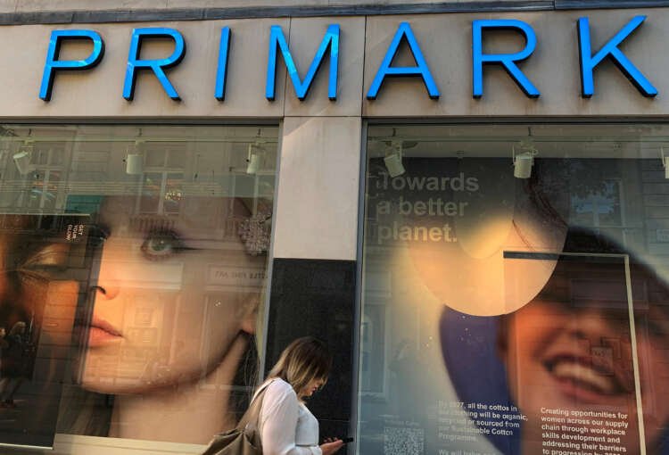 A woman walks past a Primark store window in Liverpool, showcasing budget fashion - Global Banking & Finance Review