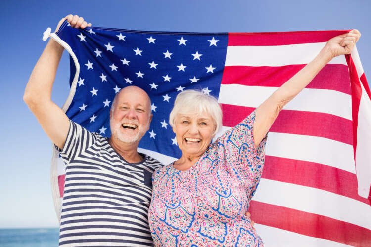 Senior couple joyfully holding an American flag, symbolizing retirement in America - Global Banking & Finance Review
