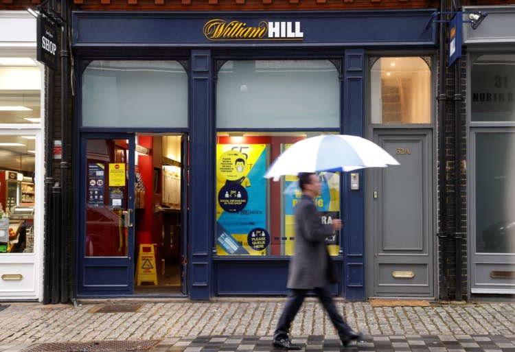 FILE PHOTO: A man walks past a branch of bookmaker William Hill in central London