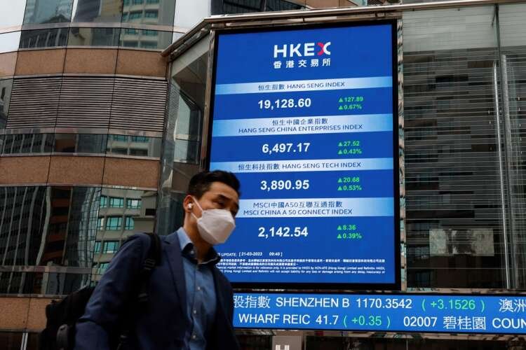 A man walks past the Hang Seng Index screen, reflecting stock market gains - Global Banking & Finance Review