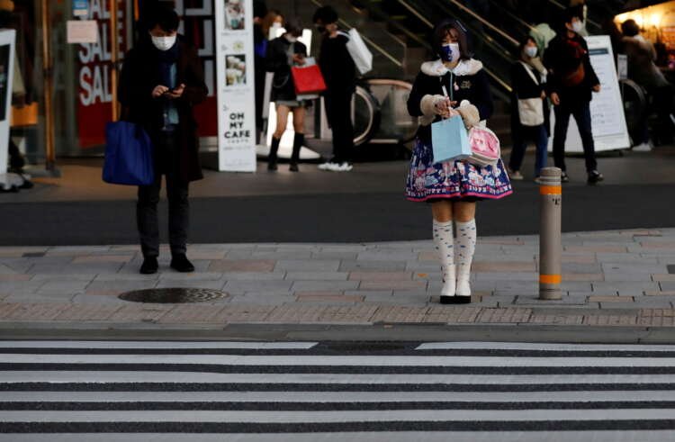 Pedestrians wearing protective masks amid the coronavirus disease (COVID-19) outbreak stand in front of a cross walk at a shopping district in Tokyo