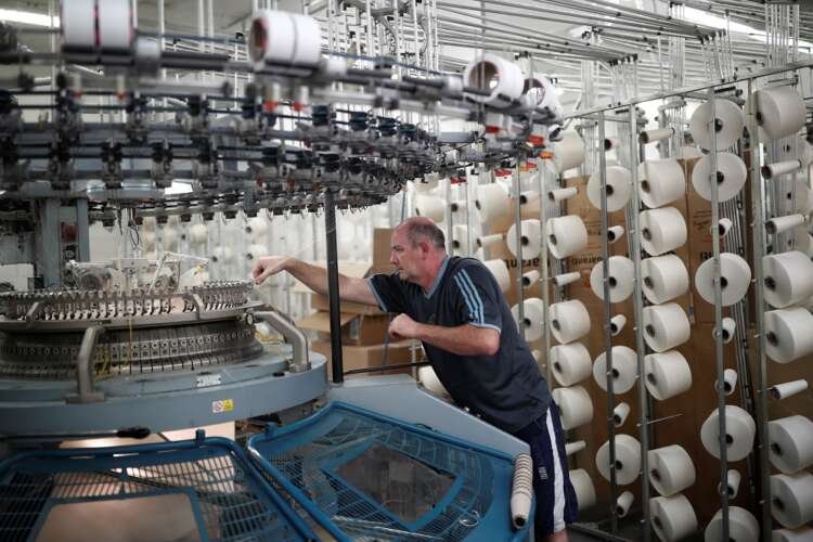 Employee at Aube Tricotage factory demonstrating euro zone industrial output growth - Global Banking & Finance Review