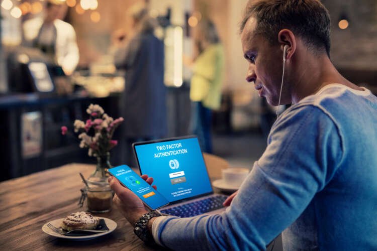Man using two-factor authentication on laptop and mobile device - Cyber security trends - Global Banking & Finance Review