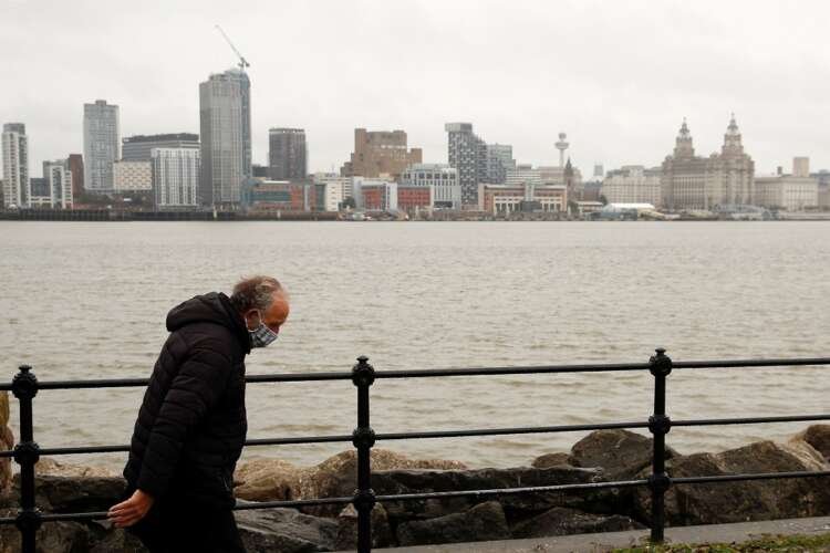 Man in face mask walks along River Mersey, highlighting UK's appeal to foreign job-seekers - Global Banking & Finance Review
