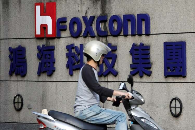 Motorcyclist rides past Foxconn logo in Taipei, highlighting Foxconn's impact on smartphone sales - Global Banking & Finance Review