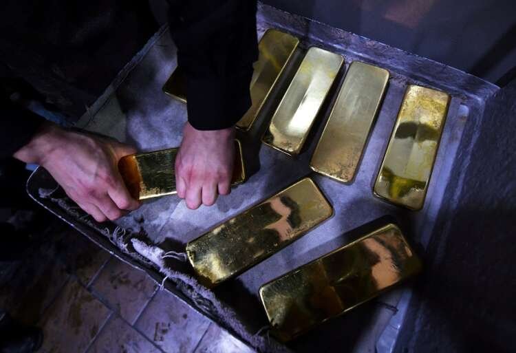 Employee handling pure gold ingots amidst rising gold prices due to geopolitical tensions - Global Banking & Finance Review