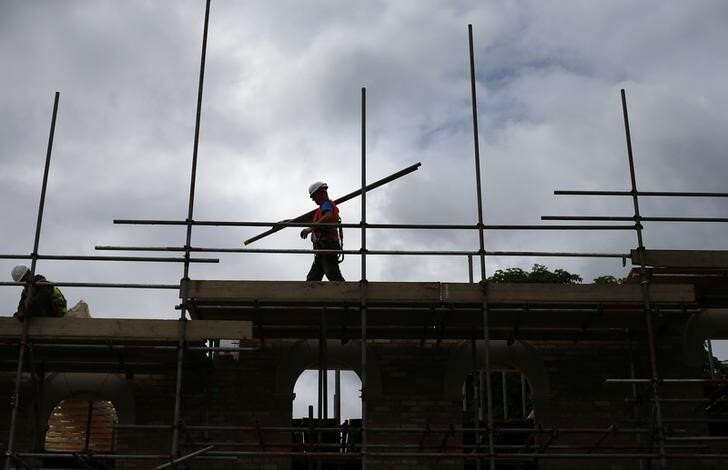 Construction worker on scaffolding building new homes in London - Global Banking & Finance Review